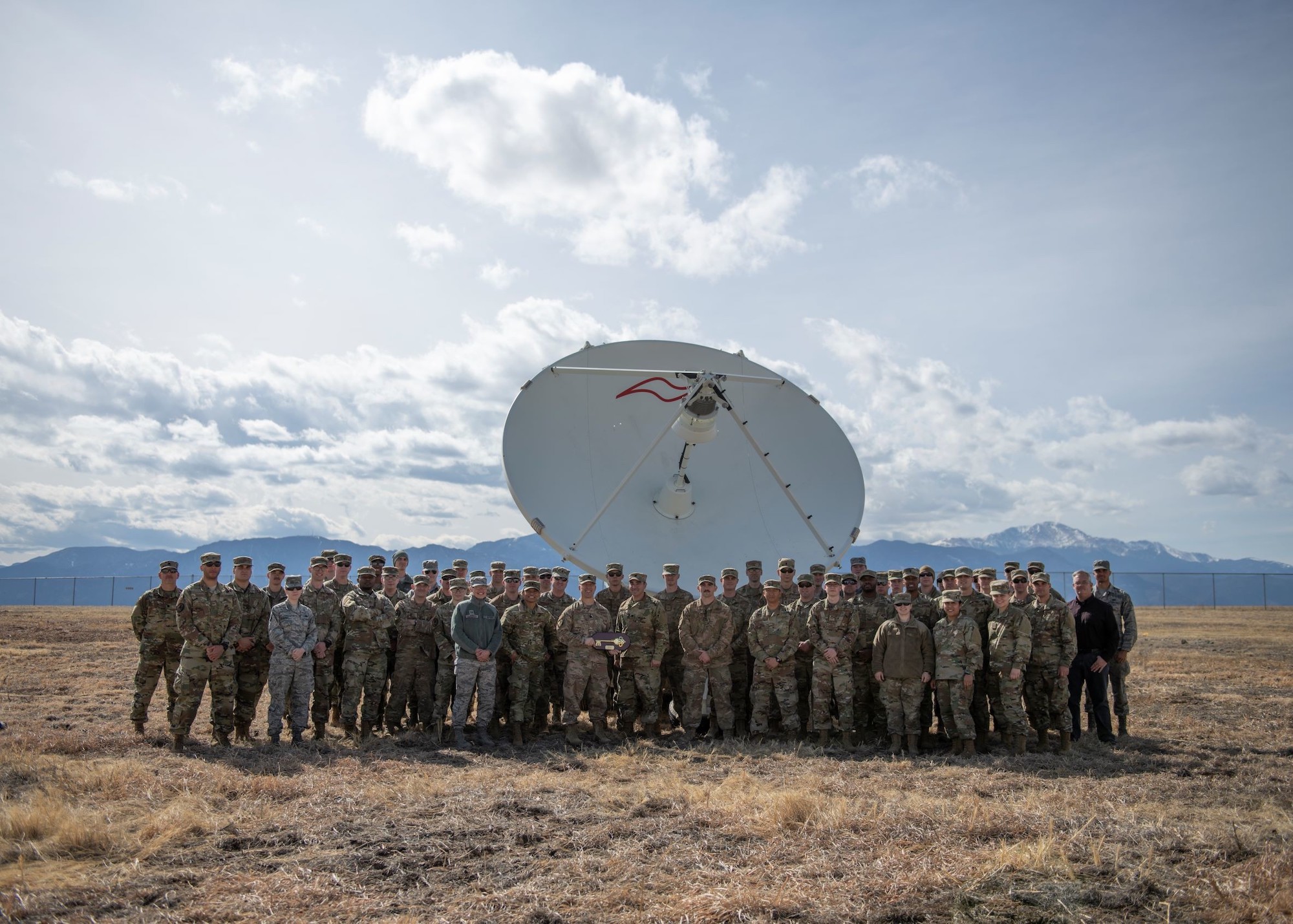 troops stand in front of a satellite dish