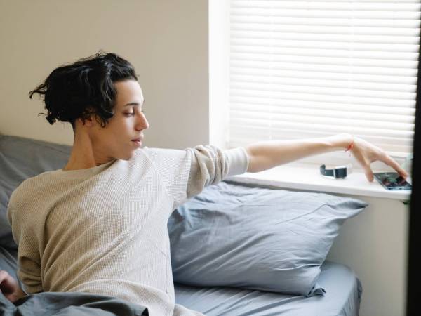 Person turning off smartphone alarm as they wake up