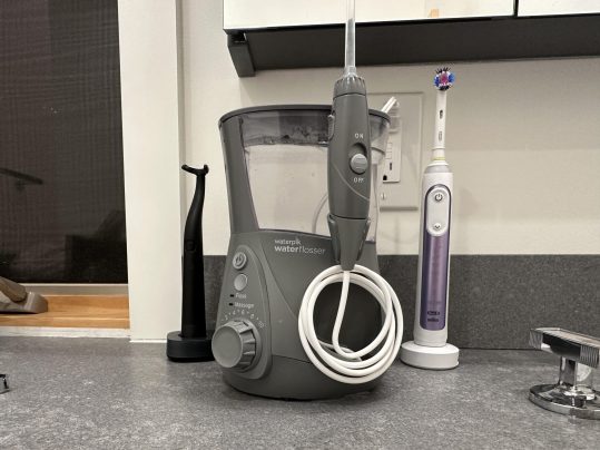 Waterpik WP-660 Flosser on a bathroom countertop next to electric toothbrush