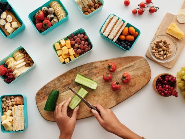 Person chopping vegetables and putting them in lunch boxes