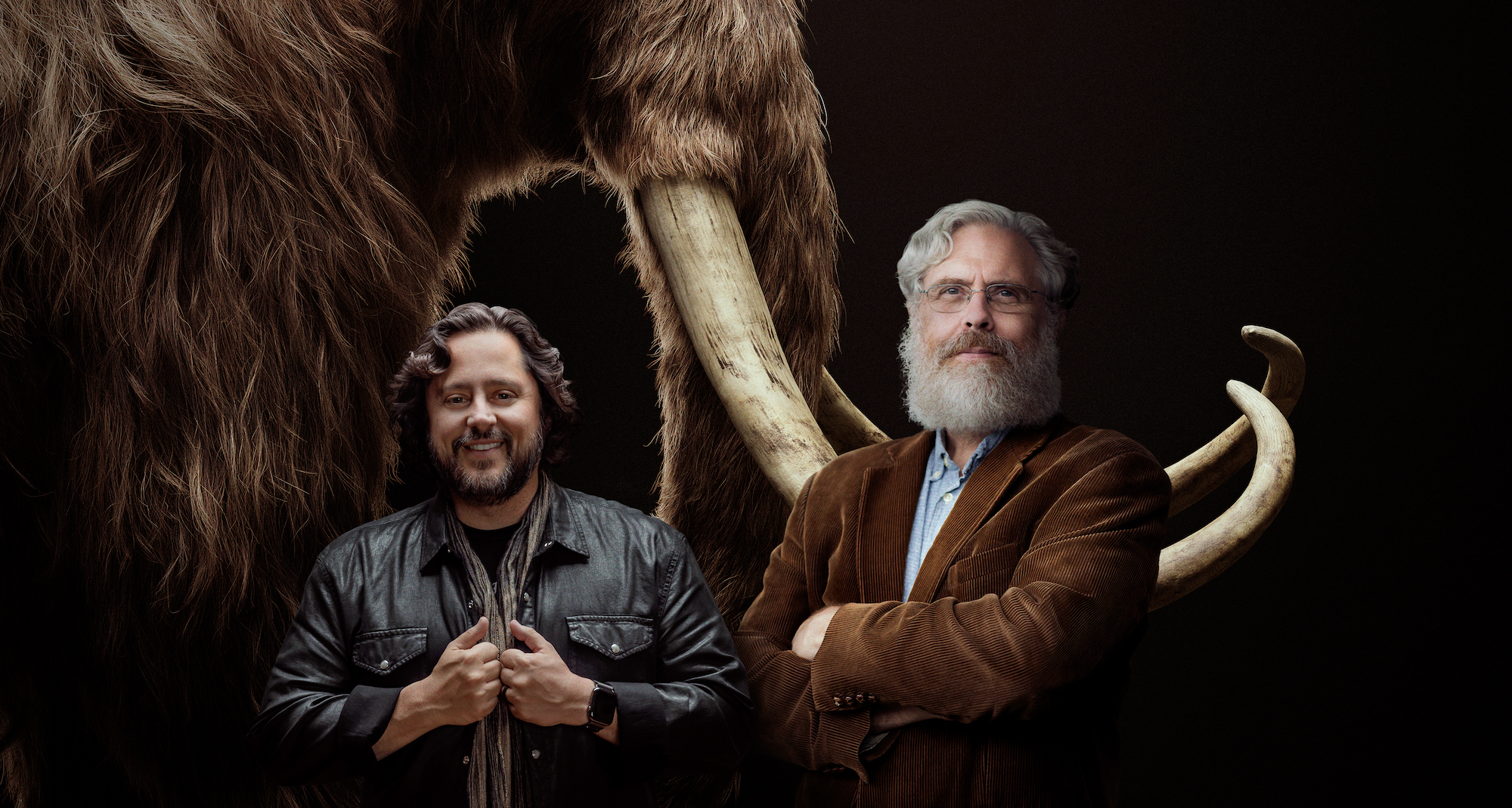 Ben Lamm and George Church in front of a woolly mammoth specimen