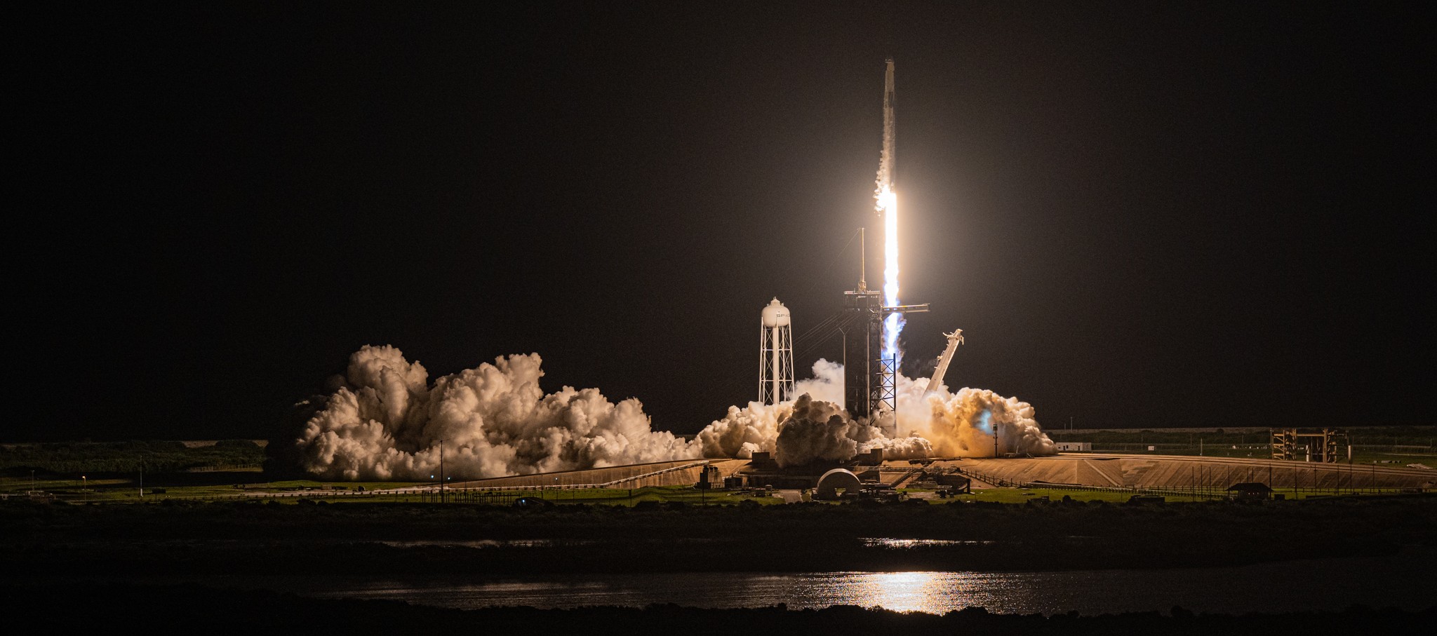 A bright rocket launches against a dark night sky.