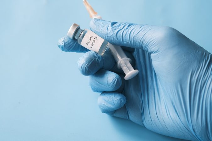 A gloved hand holding a syringe and vial.