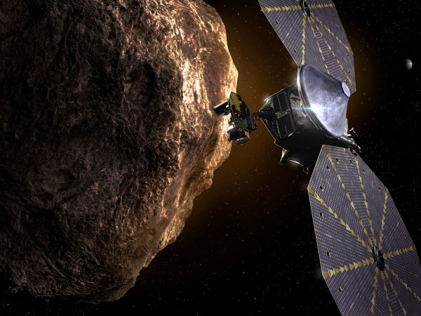 A rocky asteroid takes up the left half of the frame, and a satellite with two large solar panels sits to the right.