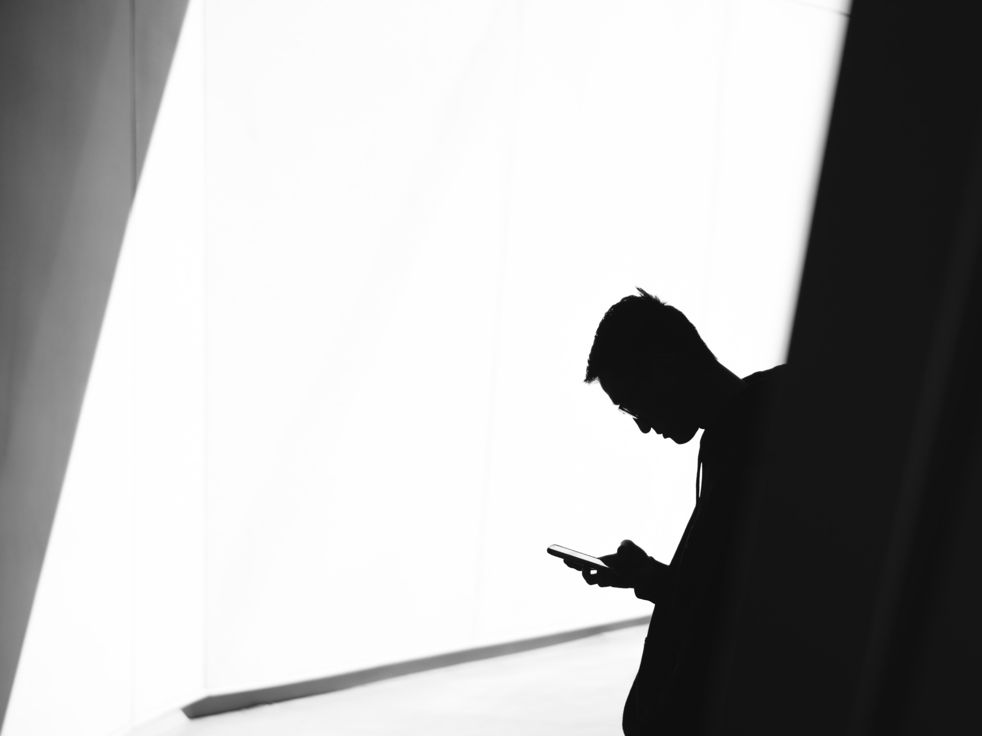 A person in silhouette using their phone.