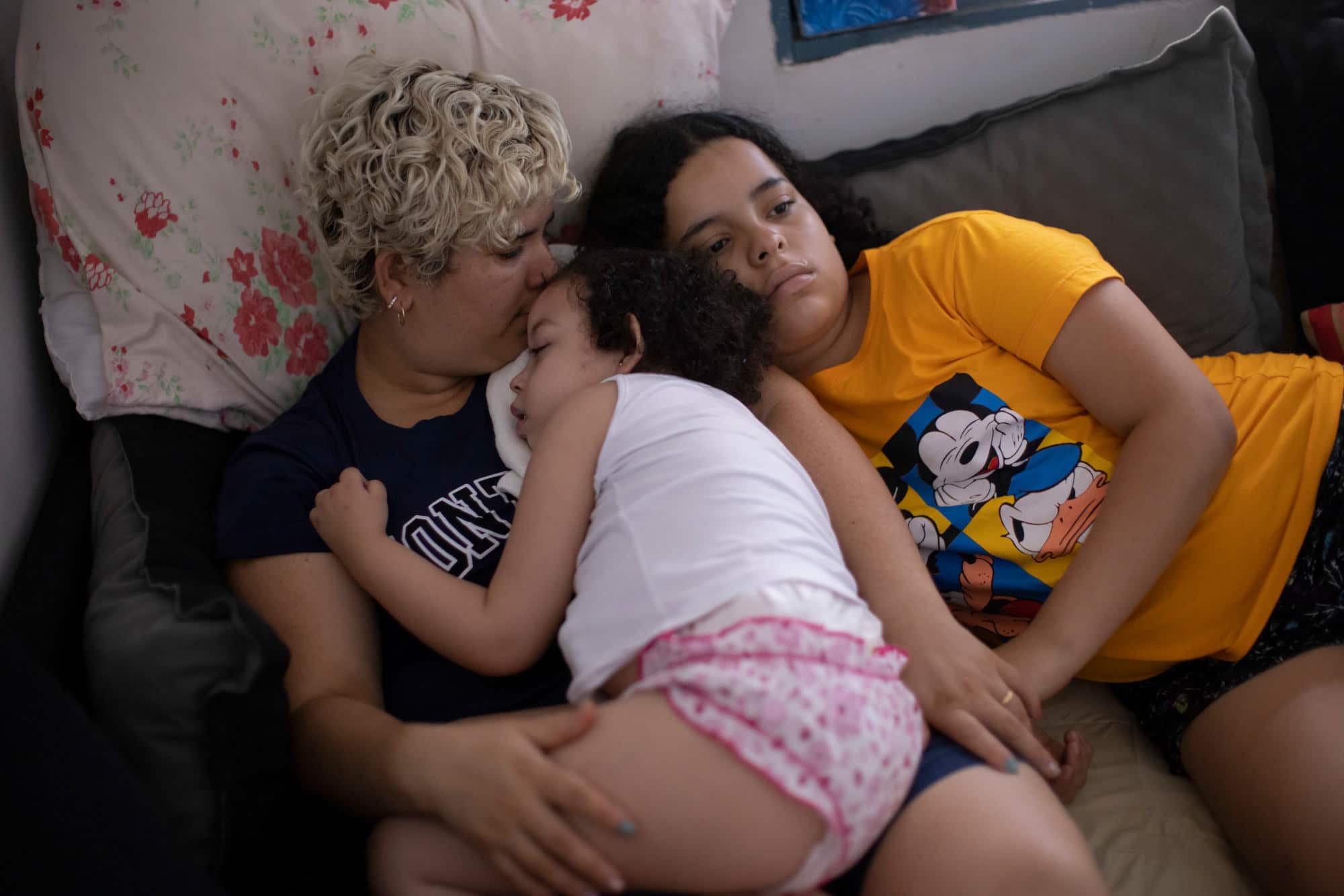 Brazilian mother sitting on couch with two daughters
