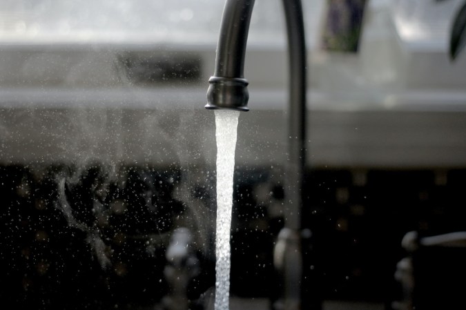 Drinking water flowing from a steel kitchen sink tap