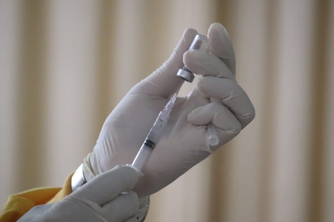 A clinician readies a vaccine for injection.