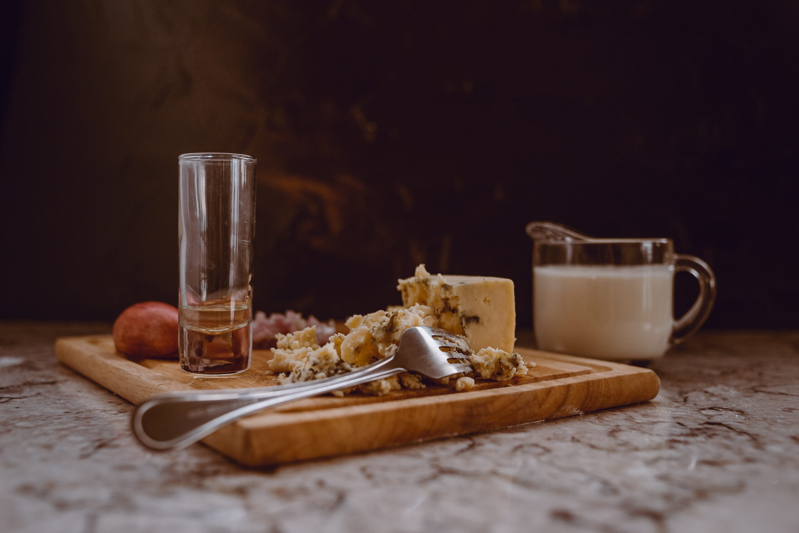 Blue cheese on a charcuterie board with an empty glass.