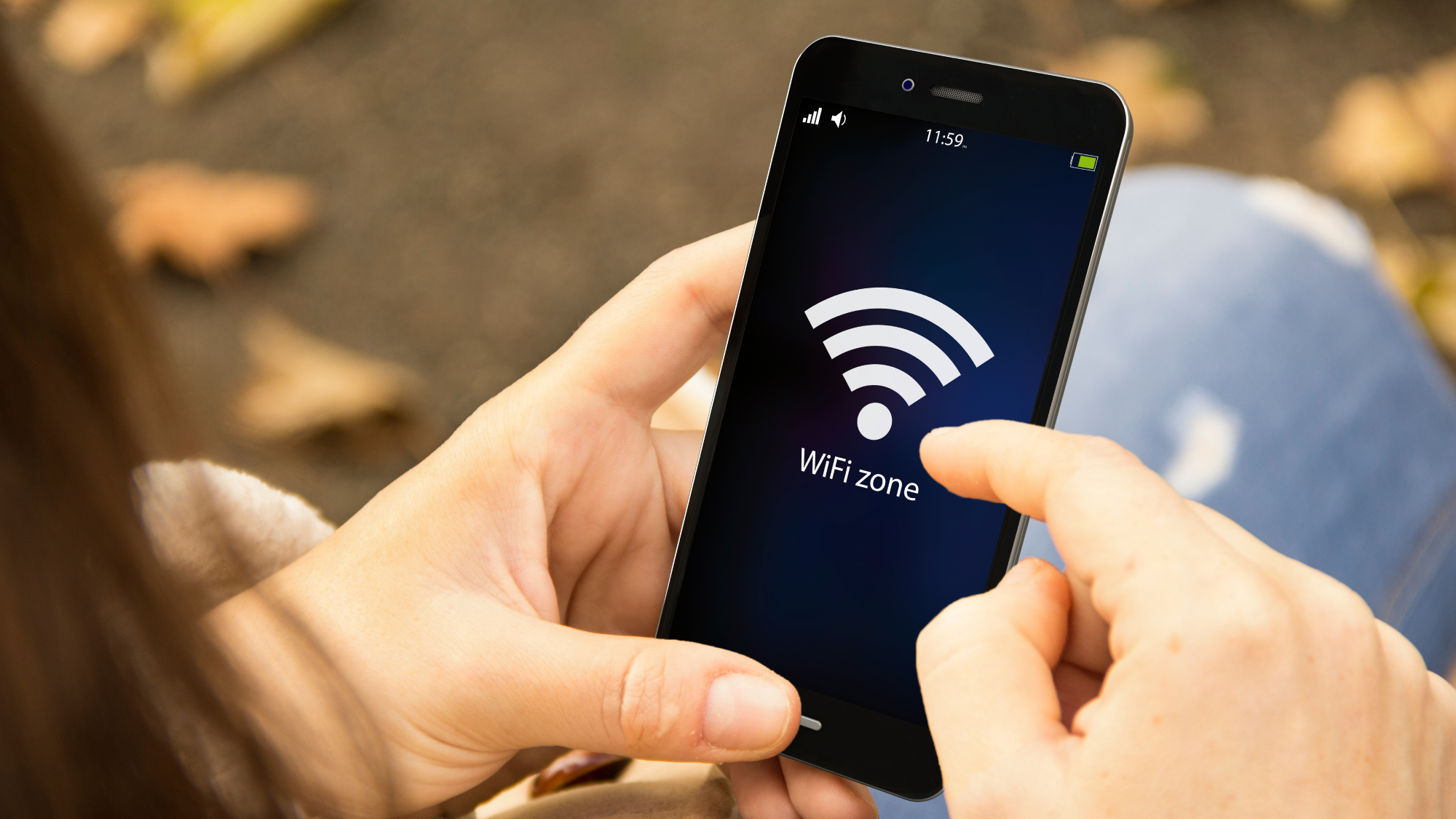 A person using a phone with a WiFi signal icon on the screen, while sitting outside.