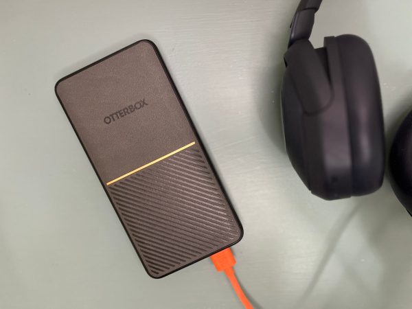  An Otterbox Performance Fast Charge Power Bank on a blue table near some headphones