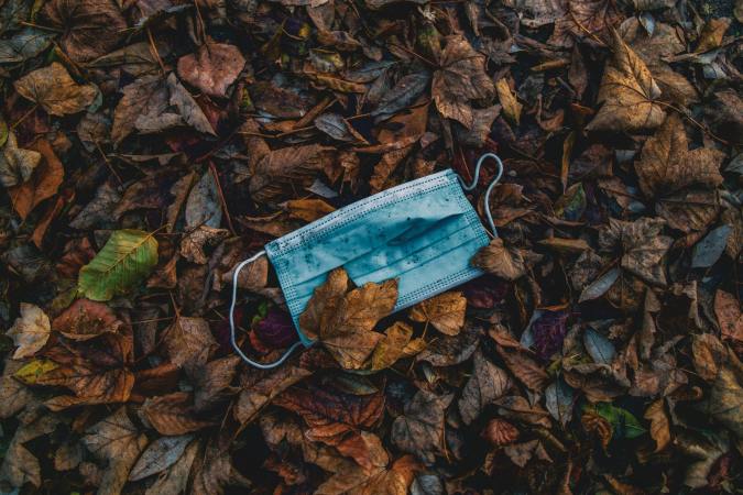 a disposable face mask in a pile of wet fall leaves