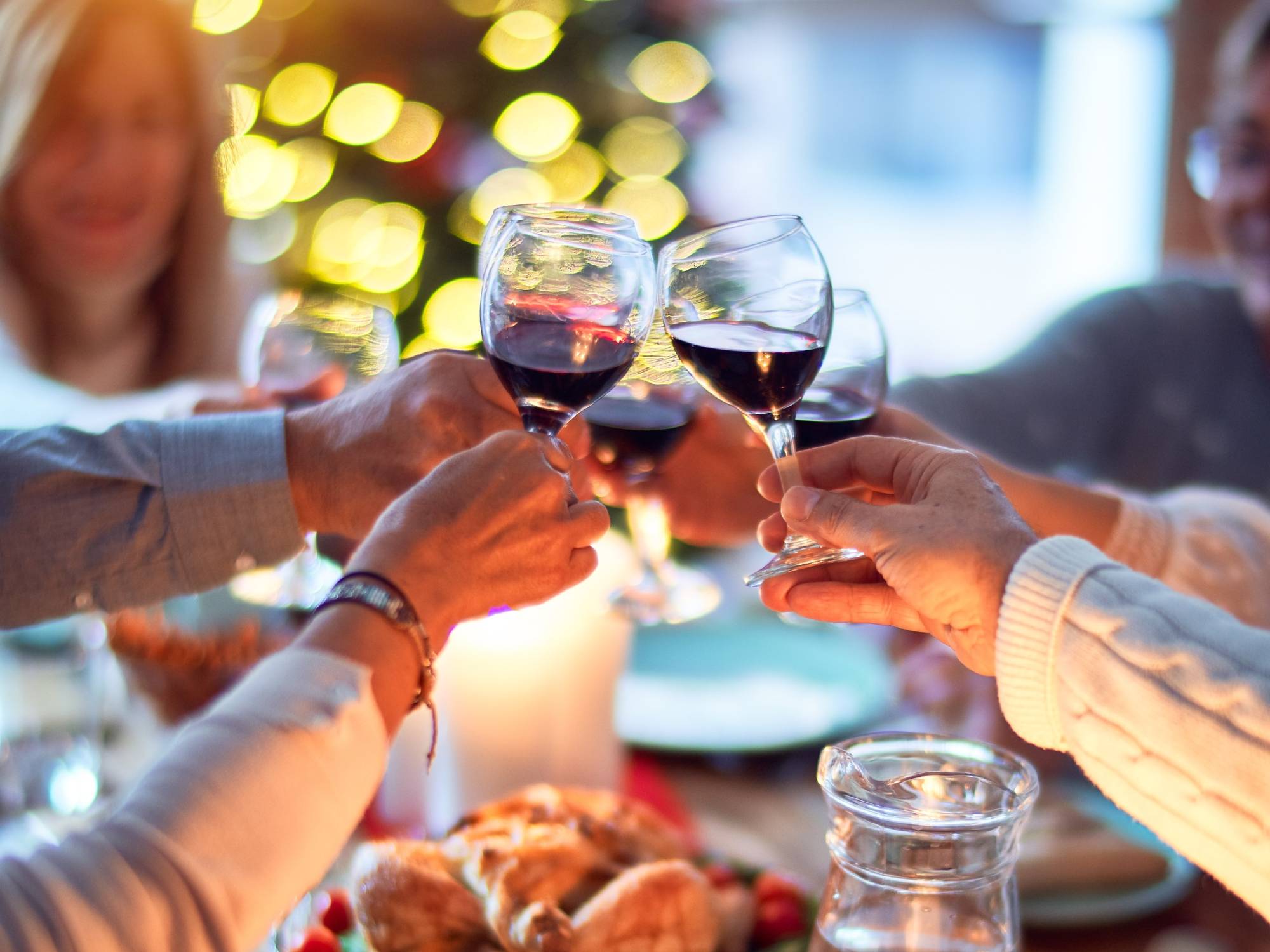 hands from family members rising glasses in celebration over dinner