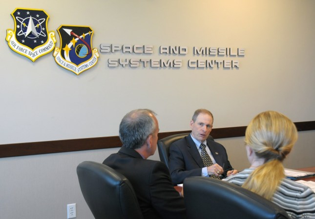 Three Air Force officials sitting around a desk at Space Force Systems Center