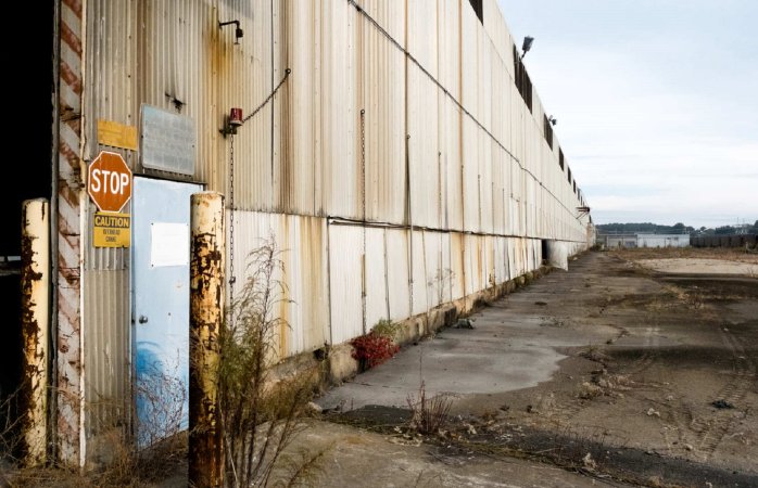 Aging walls of an old Alcoa aluminum plant on concrete polluted ground