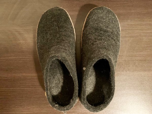  Two gray wool slippers made by Glenrups against a brown table.