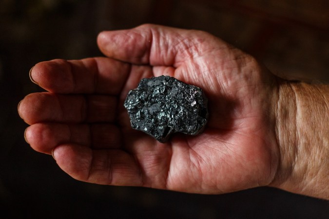 Hand holding a piece of coal.