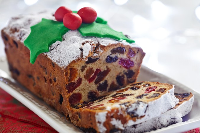 Fruitcake decorated with holiday frosting sliced on a white dish