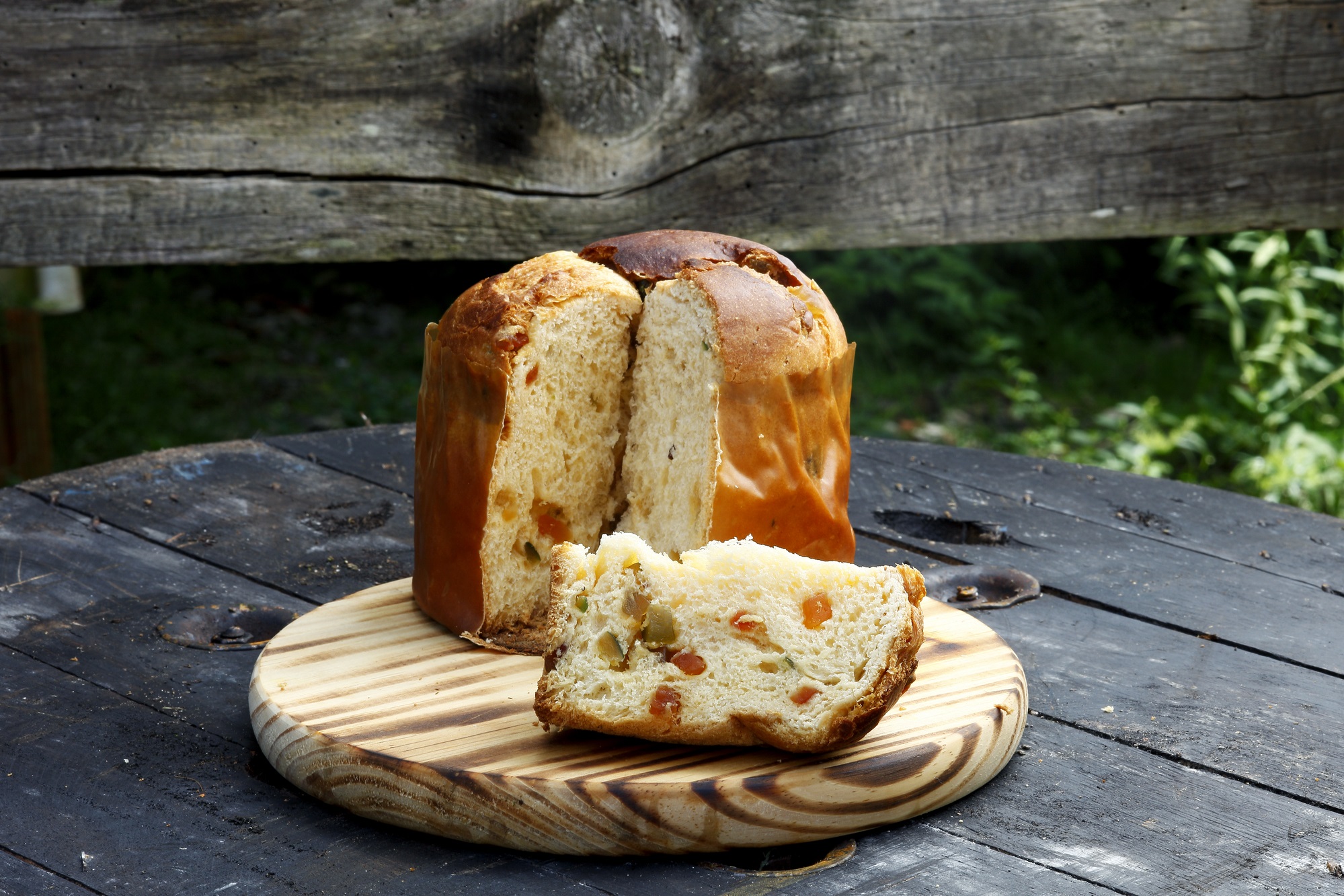 Panettone cake from Italy with candied orange pieces sliced open on a wooden cutting board