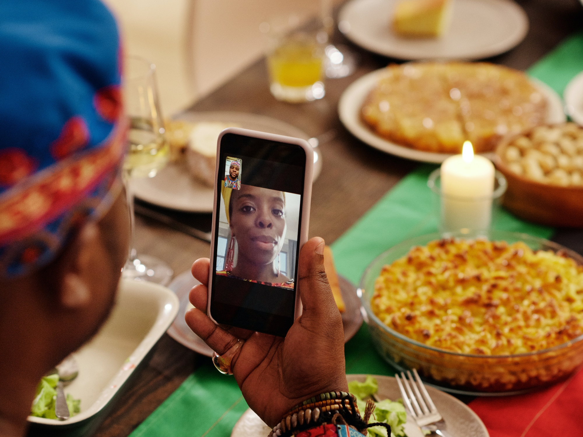 A person on a FaceTime call with someone while sitting at a table full of delicious-looking food.