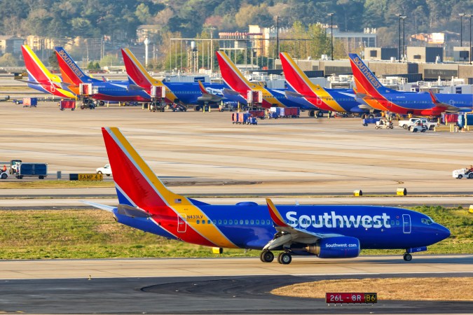 Rows of blue, red, and orange Southwest planes grounded on a domestic airport tarmac because of cancelled flights