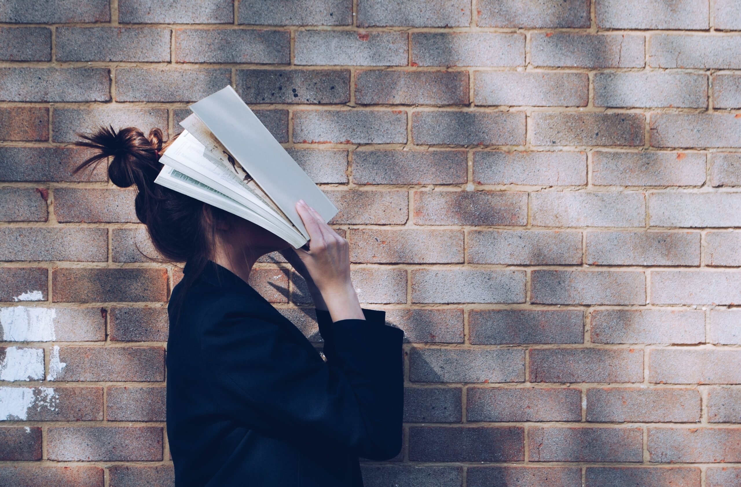 woman with book in face