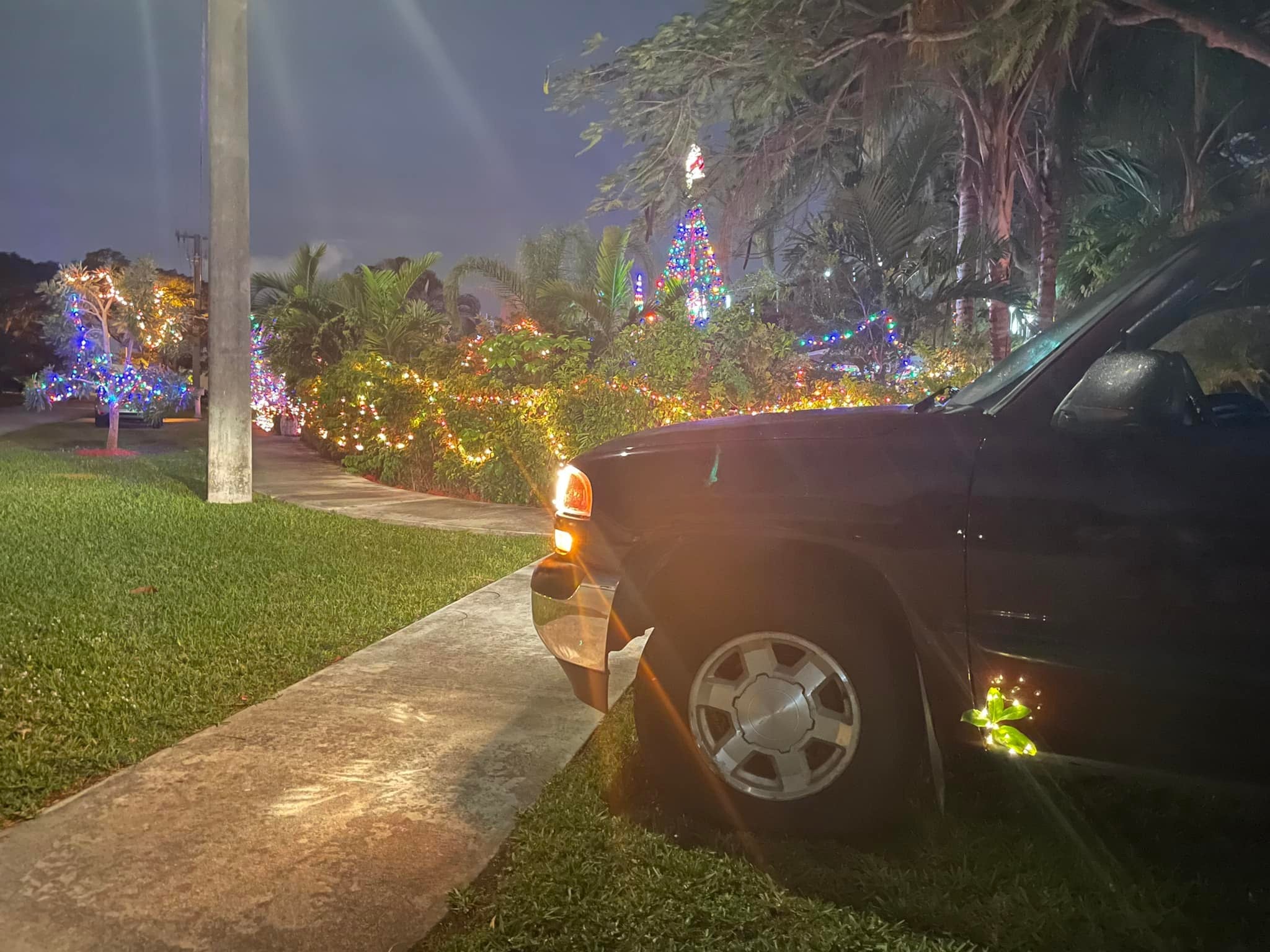 Maroon GMC pickup truck in Florida with Christmas tree lights in the background