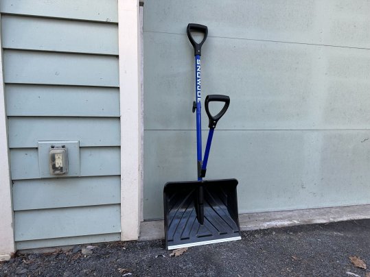 Blue Snow Joe Shovelution shovel leaning against a house