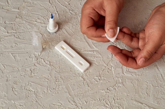 a person is pricking their finger for blood to test on a white strip with a dropper