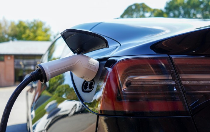 Black Tesla with white EV charger on a personal lot