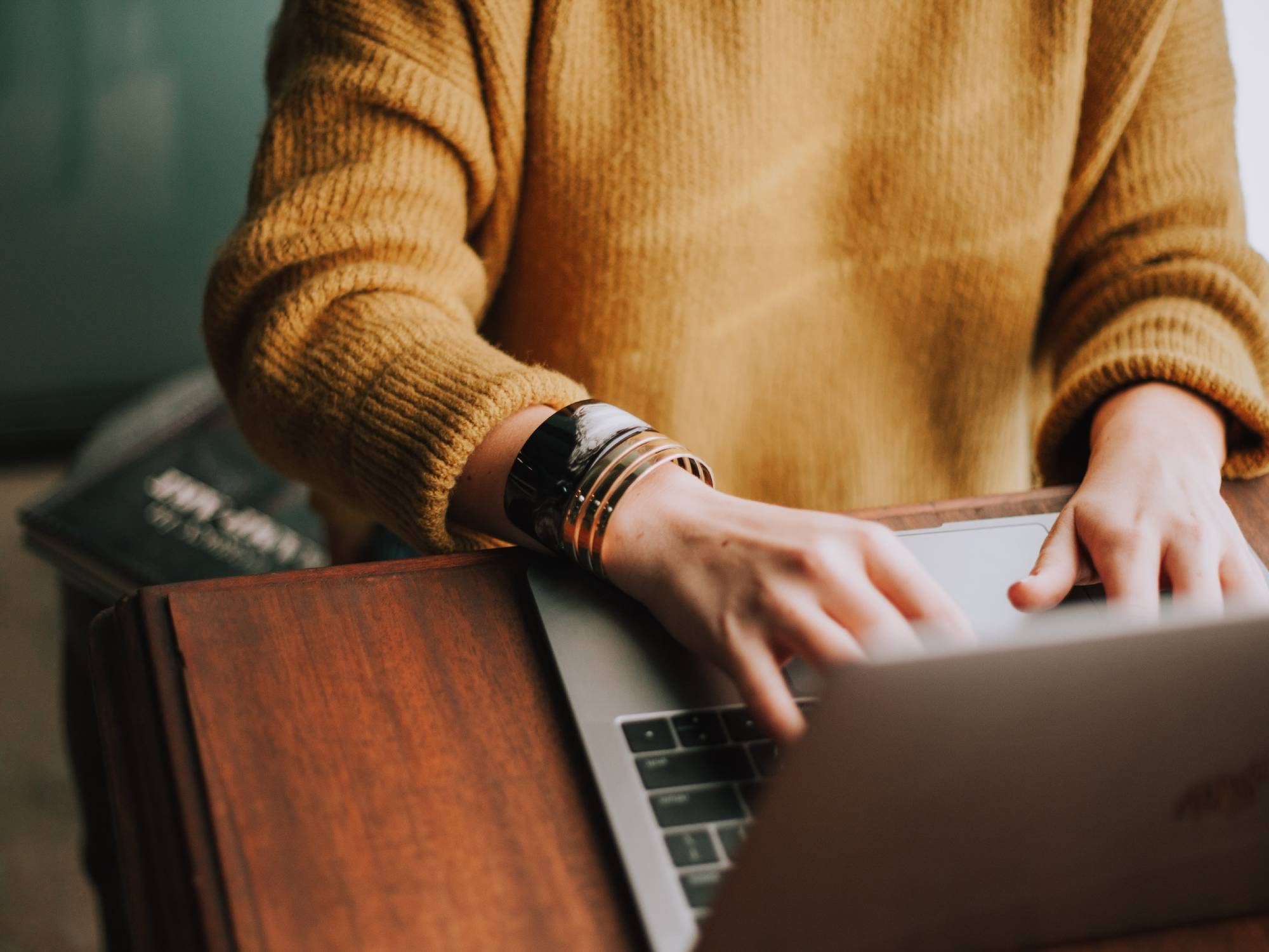 A person wearing a gold sweater and working on a laptop, possibly searching Google Drive and trying to find a lost file.