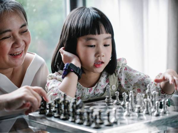 old woman and girl play chess inside the house