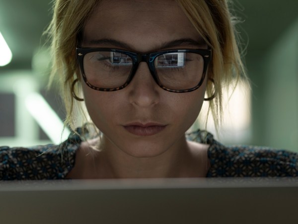 A person looking at a computer screen with photos reflecting in their glasses.