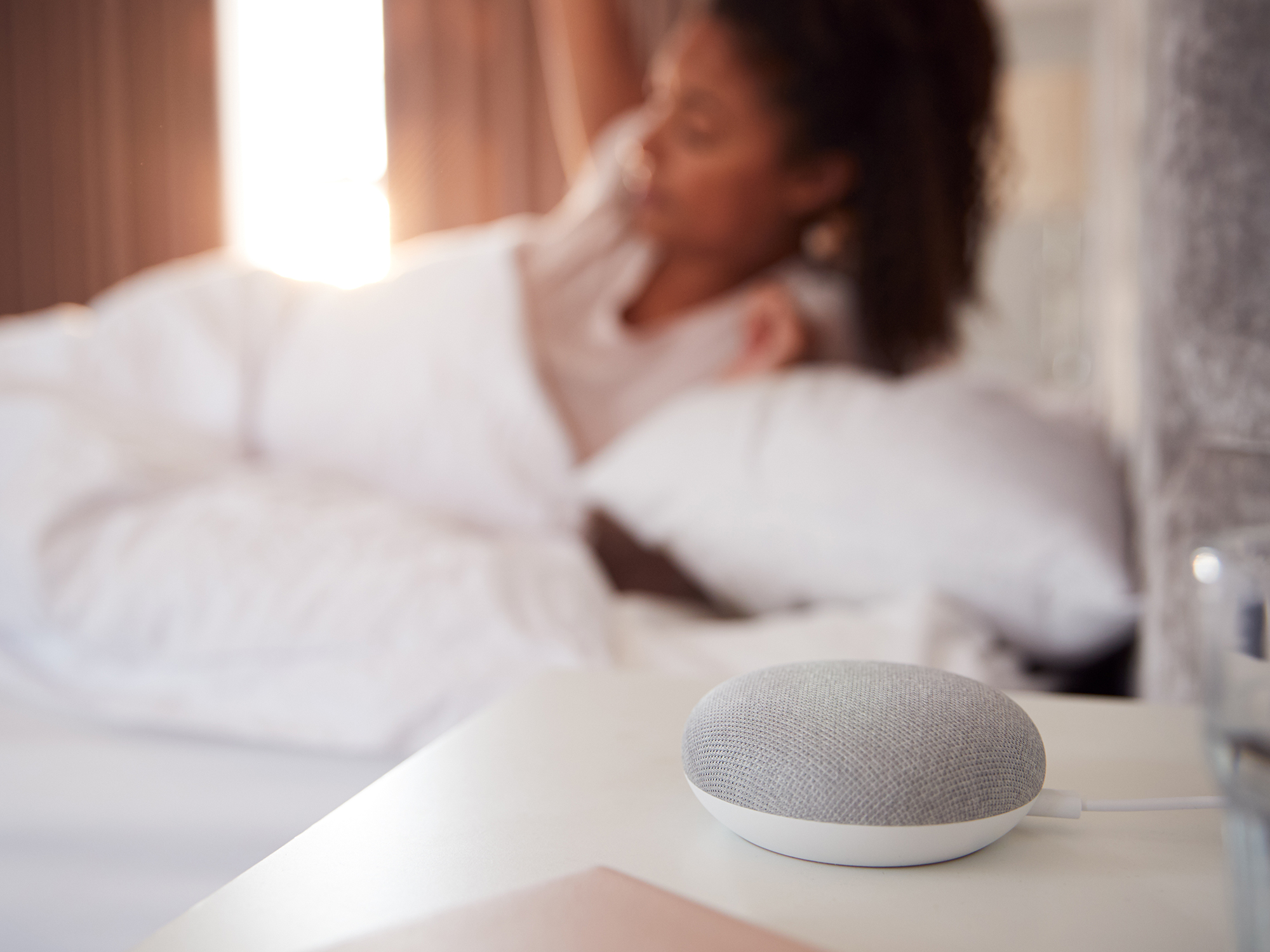 A photo of a person waking up next to a smart speaker to illustrate a story about privacy implications of the internet of things.