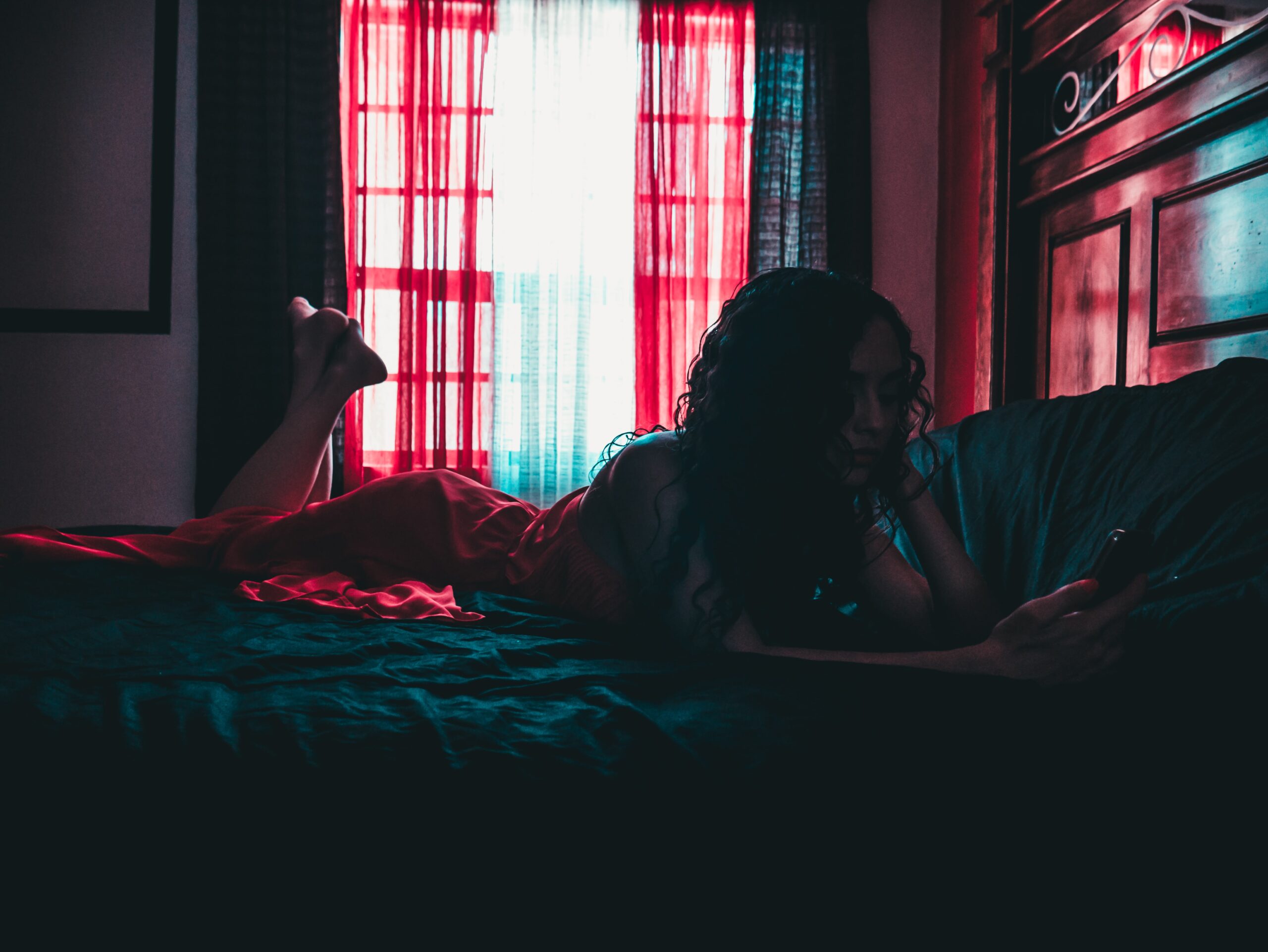 teenage girl lying on bed using phone