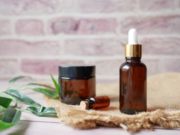 Eucalyptus essential oil on a white surface with some green leaves next to it, and in front of a brick wall.