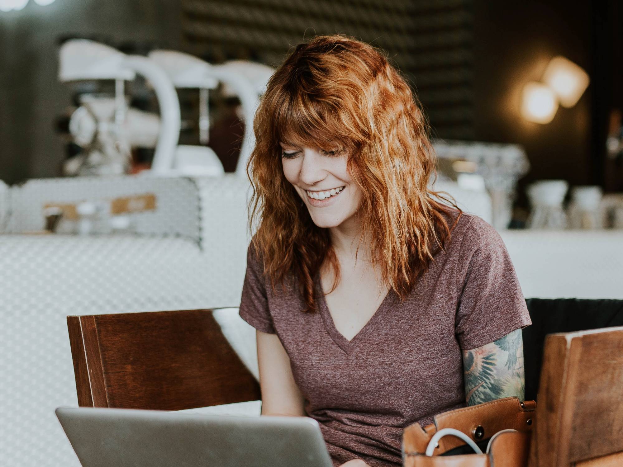 Person at cafe looking at laptop and smiling