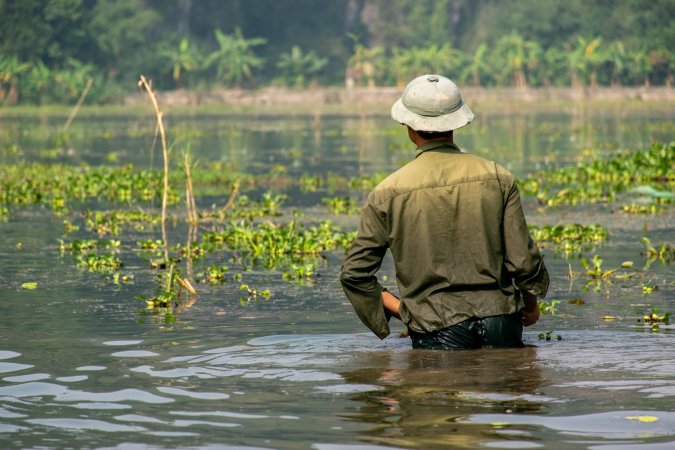 Vietnamese man wading in water after flooding.