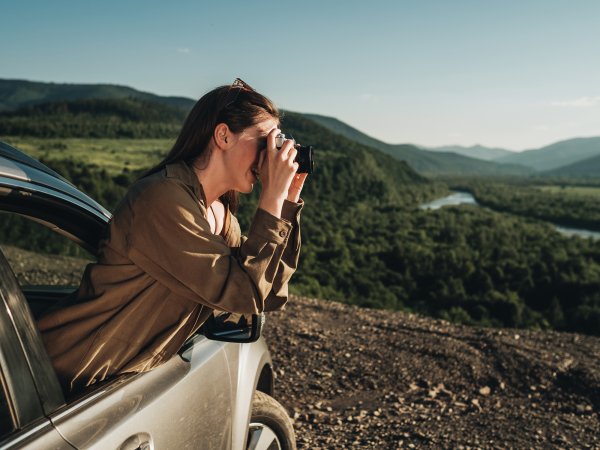 A photo of a person with a film camera traveling in their car.