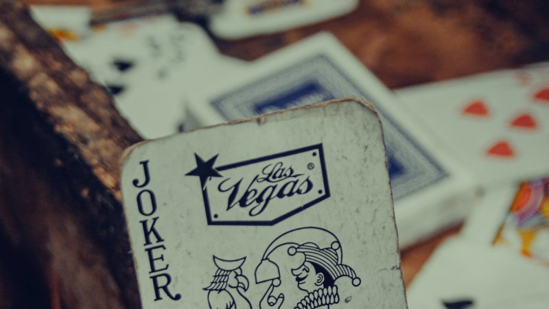 Some playing cards in a wooden drawer in a workshop, with the joker in the foreground.