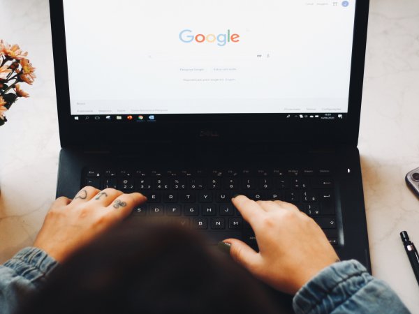 hands on keyboard of laptop with google on the screen