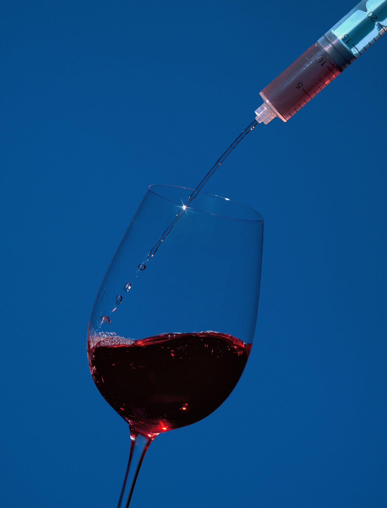 Syringe pours red wine into glass