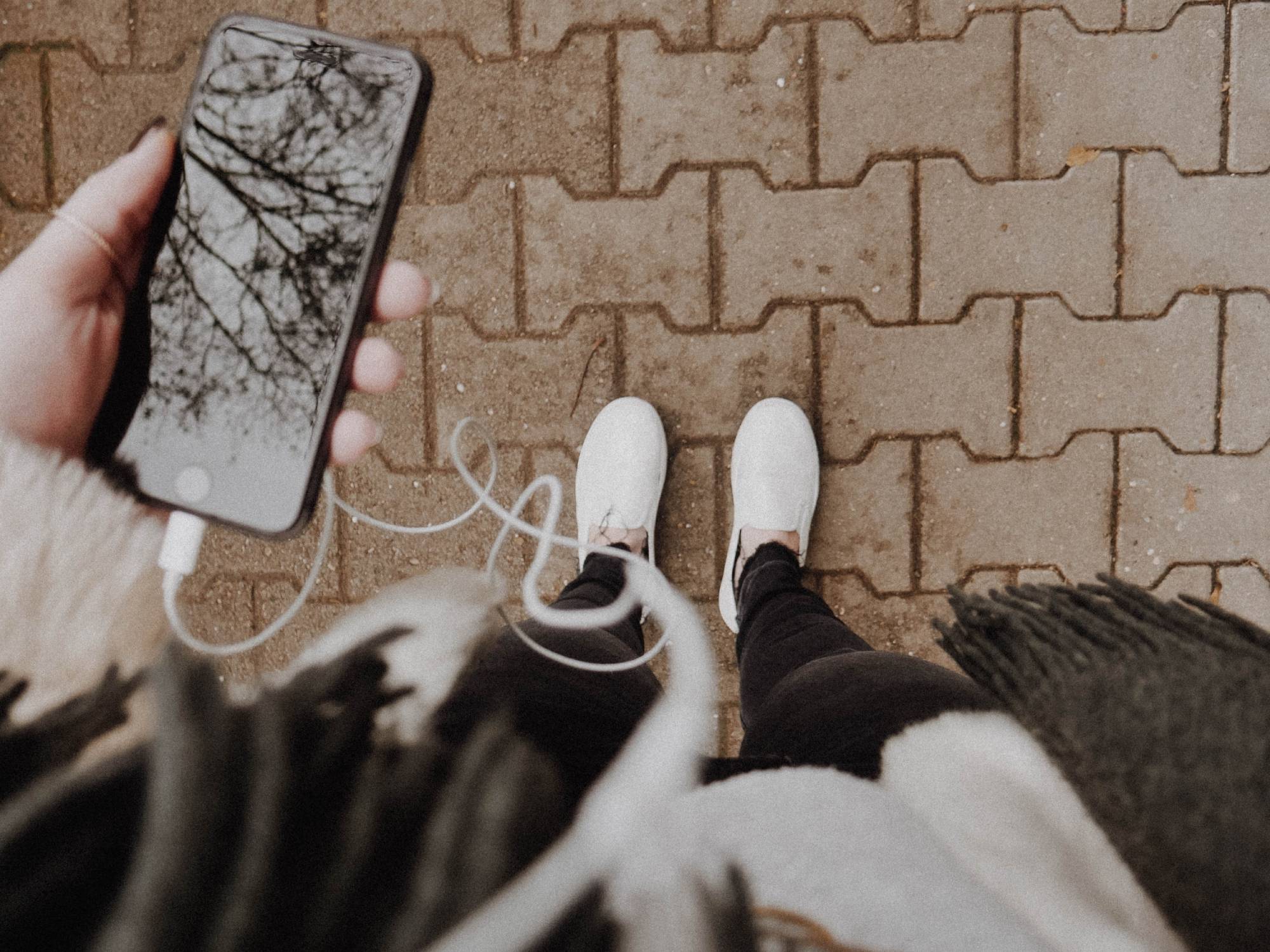 person holding phone connected to earbuds