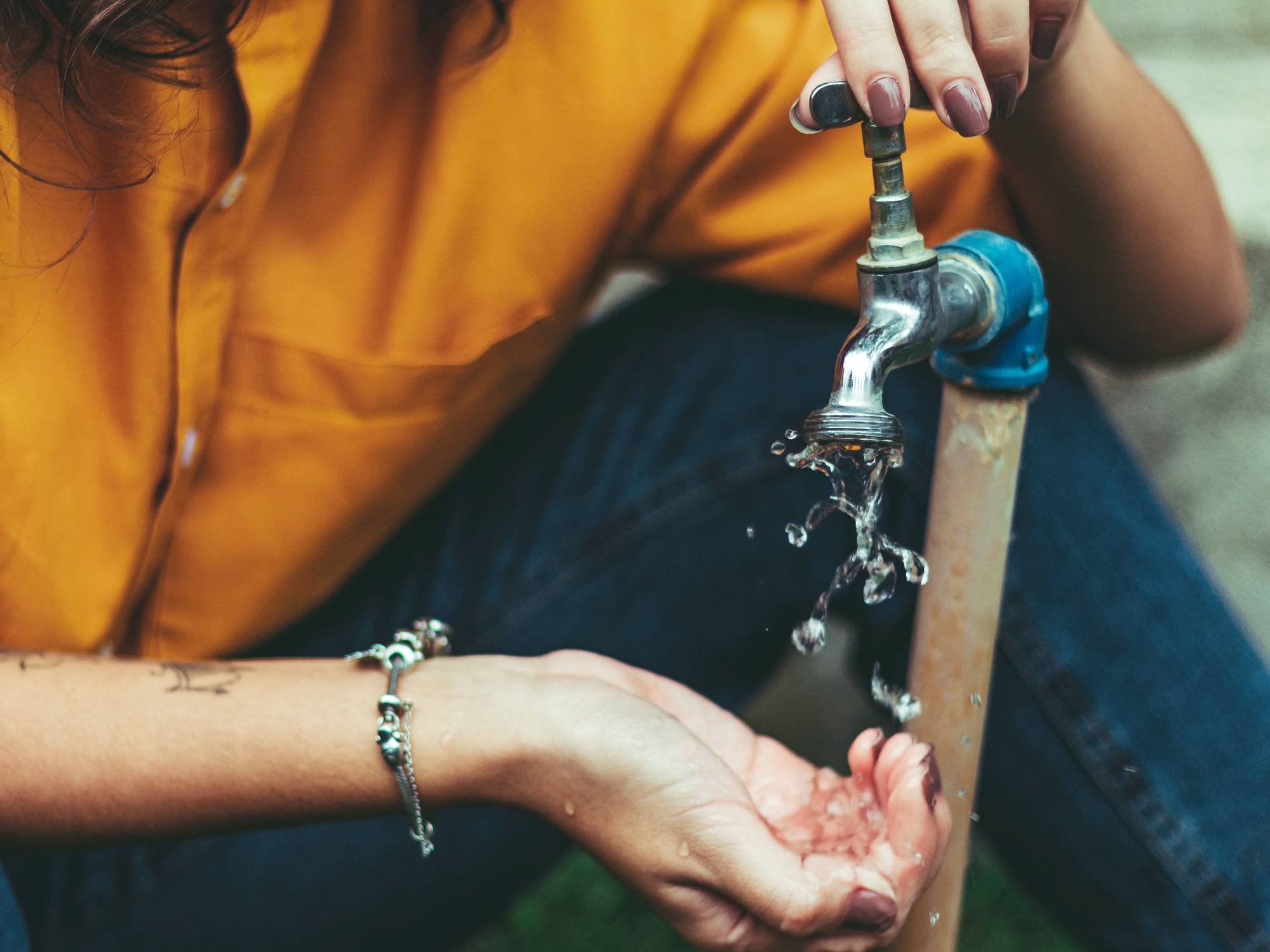 person opening faucet with water flowing