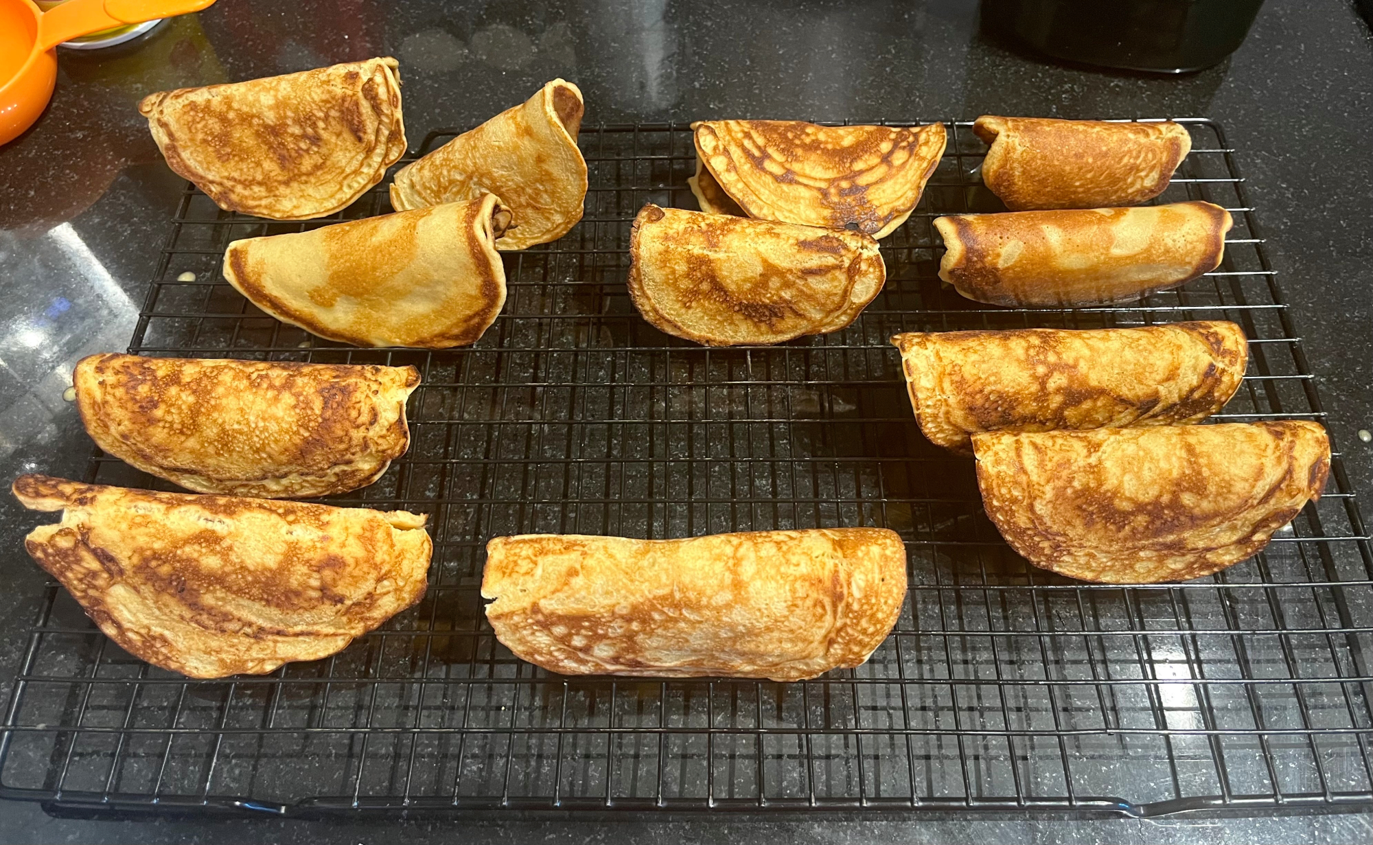 Twelve homemade waffle cones resting on a cooling rack.