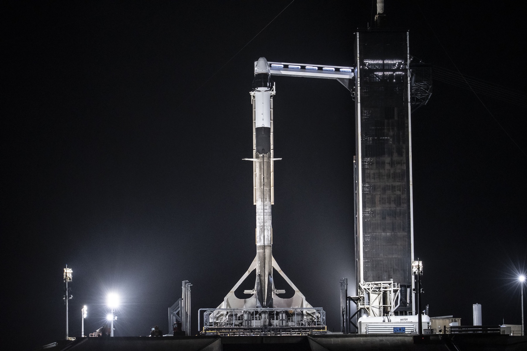 a rocket stands on a launch pad late at night