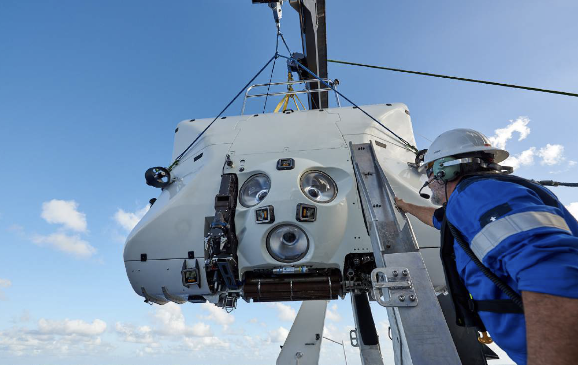 a submersible hangs from a crane on a boat