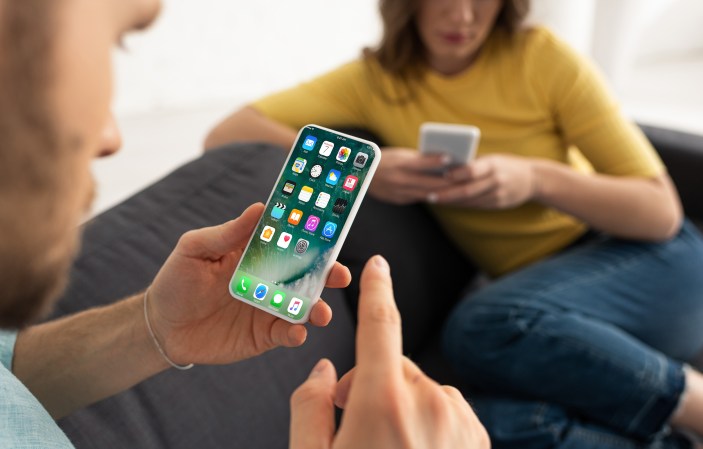 Close up of man and woman using their smartphones on couch