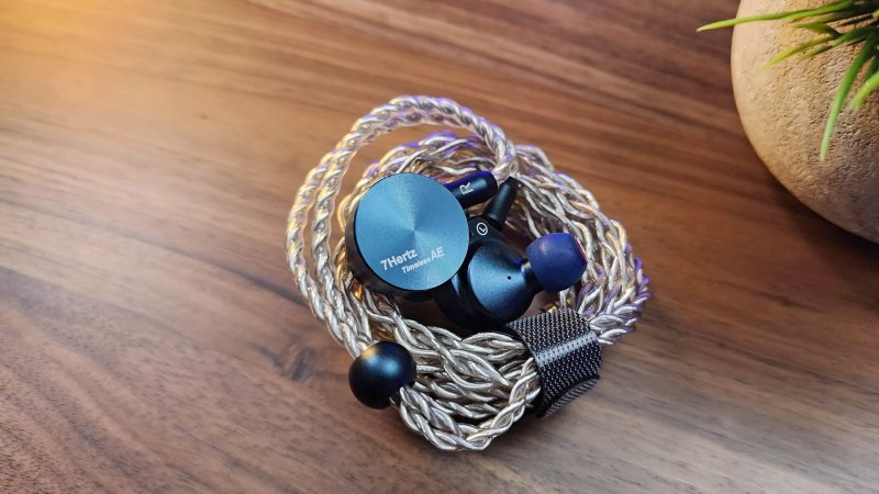  Image showcasing 7Hz Timeless AE earbuds styled alongside their coiled cable on workspace 