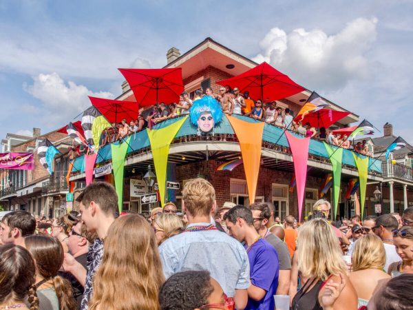 A crowd in front of a bar covered in colorful flags.